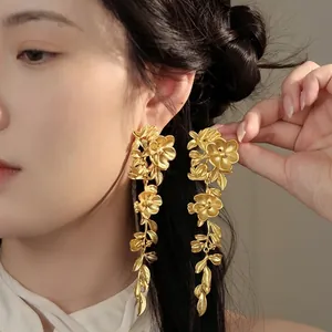 Detailed close-up of vintage floral matte gold drop earrings on a model's ear