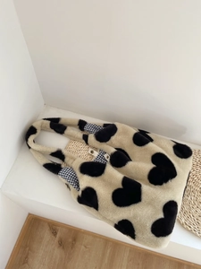 Close-up of fluffy heart-pattern tote with checkerboard lining and metal snap button
