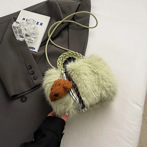 Green plush handbag with teddy bear charm shown in a stylish minimalist flatlay setting
