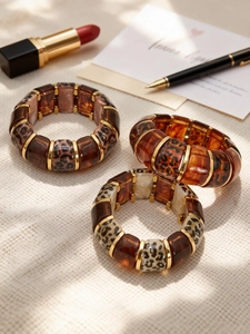 Three leopard print resin bracelets with 18k gold accents in deep brown and amber