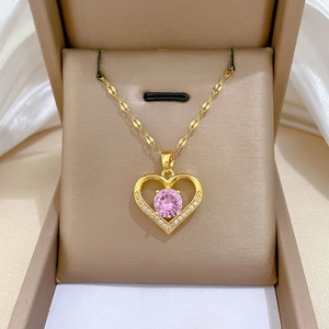 Macro detail of heart pendant with pink zircon and white crystals on gold chain