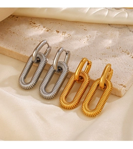 Detailed macro of gold and silver geometric oval earrings on silk and stone base