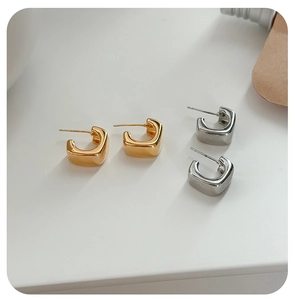 Detailed view of polished square C-shaped earrings in gold and silver finish