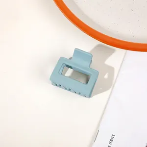 Detailed view of a matte blue geometric square hair claw clip on a modern white desk