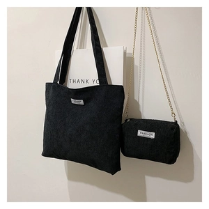 Detail of black corduroy tote bag set with matching small chain pouch on white wall