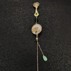Détail d'une broche chinoise vintage avec perles et pendentifs en émeraude verte