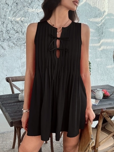 Detail of black sleeveless mini dress featuring pleated texture and lace-up cutout front