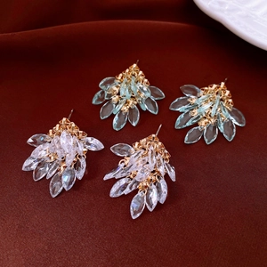 Detail of cluster earrings with blue and white teardrop crystals on golden metal base