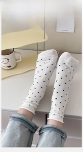 Detailed view of white cotton socks with black polka dots and elastic ribbed cuffs