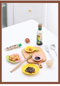 Close-up of ceramic sunflower and cherry blossom sauce dishes with a green leaf rest