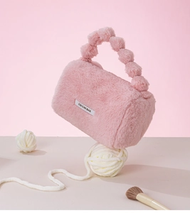 Detailed macro shot of a pink faux rabbit fur handbag with cute fluffy pom-pom handle