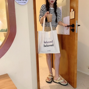 Lifestyle view of white canvas tote bag with beloved embroidery and long shoulder straps