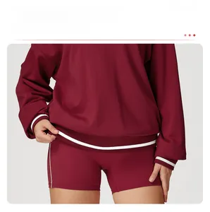 Detail of burgundy sweatshirt showing ribbed cuffs and hem with white contrast stripes