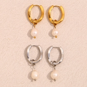 Minimalist U-shaped 18K gold and silver earrings with pearls on textured stone surface