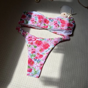 Detail of pink floral bikini set with ruffle edges on beige woven background