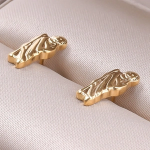 Macro shot of gold-plated stainless steel ghost-shaped earrings on a beige jewelry box