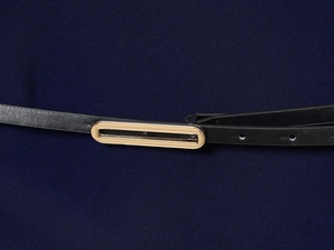 Detail of black leather belt with gold rectangular metal buckle on navy fabric