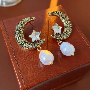 Close-up of vintage gold crescent moon and star earrings with irregular white pearls
