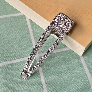 Silver metal hair clip with embossed texture on book background for women