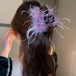 Detail of a large purple feather hair claw with rhinestones on a woman's hair bun