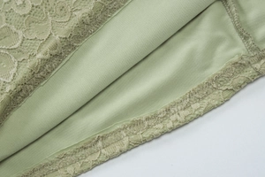 Dettaglio ravvicinato del pizzo verde e cuciture di un abito da festa sexy con scollo a V