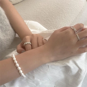 Close-up of 925 sterling silver rings and white pearl bracelet on a soft fabric