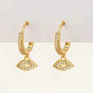 Close-up of gold earrings with micro-pave zircons and creative lip-shaped pendants
