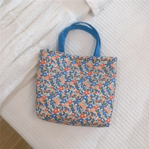 Top view of floral canvas tote bag with blue handles and bronze snap button closure