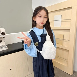 Minimalist white plush teddy crossbody bag for children shown in a cozy indoor setting