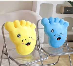 Close-up of soft plush big feet pillows with embroidered facial expressions on a chair