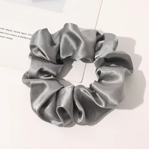 Detail shot of silver-grey silk scrunchie with soft satin texture and elegant sheen