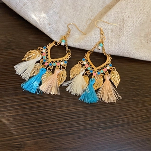 Detail of bohemian leaf tassel earrings with golden heart charms and colorful beads