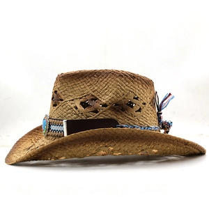Détail d'un chapeau de cowboy en paille ajouré avec perles turquoise ethniques et pompons