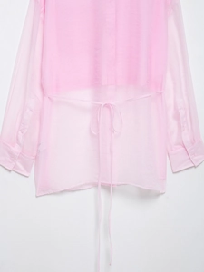 Dettaglio del fiocco posteriore sulla camicia rosa trasparente in organza a maniche lunghe