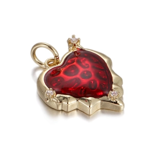 Macro view of heart-shaped gold pendant with red resin inlay and small crystal accents