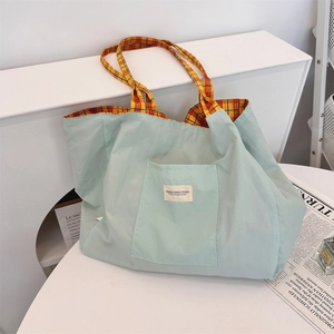 Detail of canvas tote bag showing mint green exterior and orange plaid lining