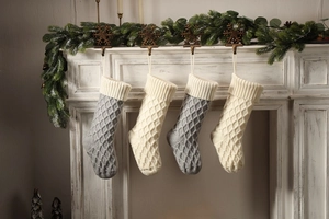 Detailaufnahme grauer und cremefarbener Strick-Weihnachtssocken mit Rautenmuster am Kamin