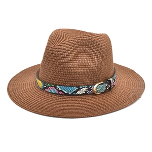 Detail of a brown woven straw fedora hat featuring a rainbow snakeskin band with a gold buckle