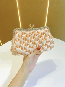 Primo piano di pochette da sera in raso champagne con trama a pieghe e bordo di strass