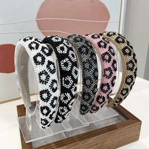 Handmade leopard print bead headbands in five colors displayed on a modern stand