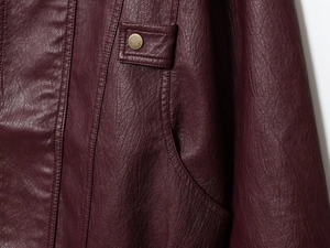 Detailed macro view of burgundy PU leather jacket featuring pocket flap and vintage metal button