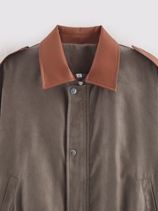 Close-up of suede jacket collar with contrast leather trim and silver snap buttons