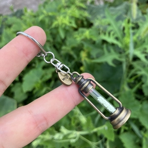 Close-up of vintage bronze hourglass pendant with white sand and a Wish engraved tag