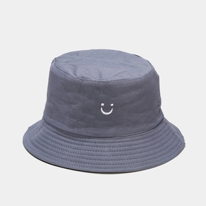 Detailed view of the white smile embroidery on a dark grey cotton bucket hat fabric