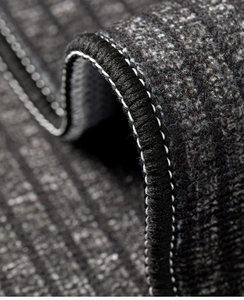 Macro detail of high-density edge stitching and non-slip texture on dark gray kitchen mat