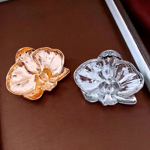 Elegant gold and silver orchid flower brooches with polished texture on leather background