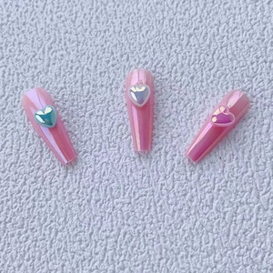 Sparkly aurora heart resin nail art charms with iridescent finish on pink false nails