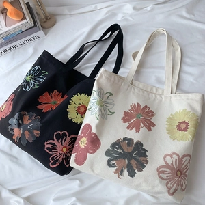 Detail of floral printed canvas tote bags in black and beige on white fabric