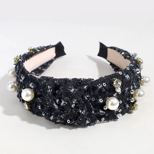 Detail of black tweed headband with faux pearls, rhinestones, and sequins on white background