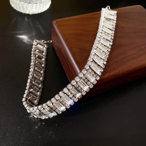 Detailed view of silver wide-band necklace with luxury rectangular and round rhinestones